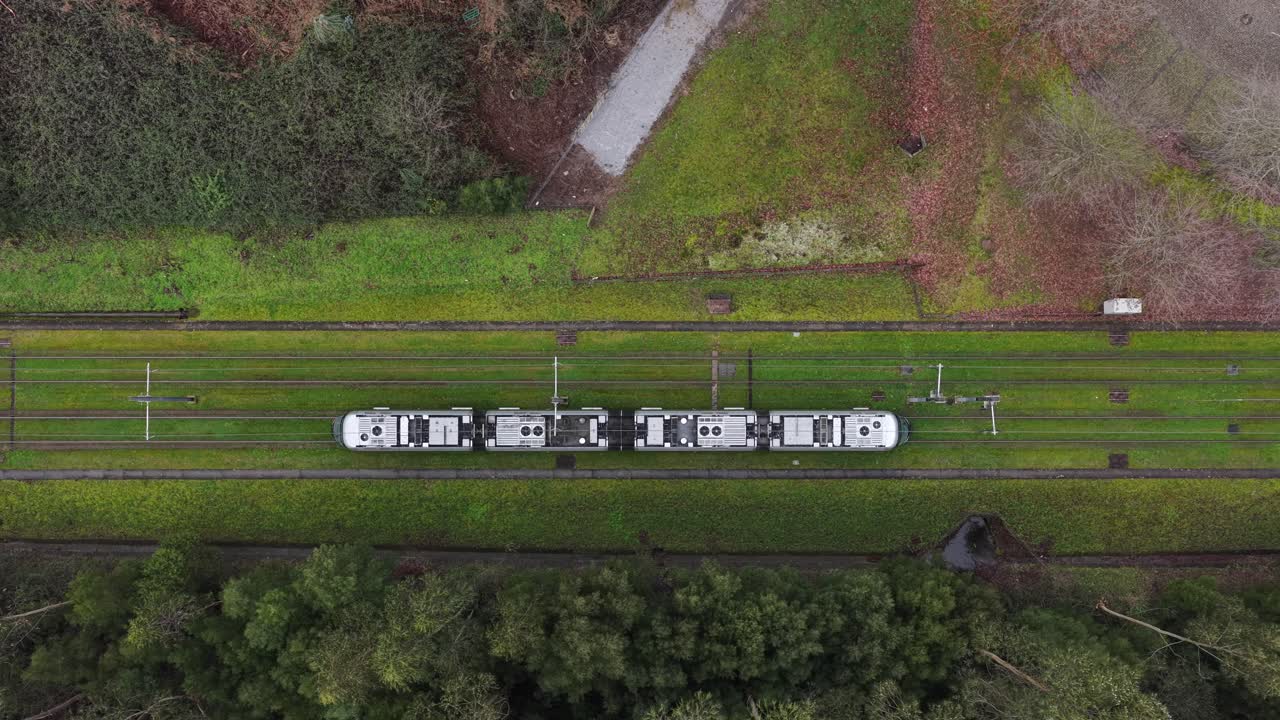 Eletrical subway riding on the tracks with grass. Sustainable public transportation top down view