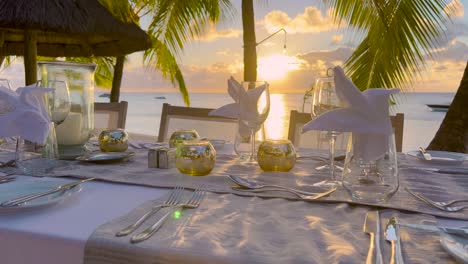 table by sea with sweet things snacks, drinks for banquet on fresh air outdoors. on white tablecloth decorating with yellow flower dishes, vases with decorations, various glasses