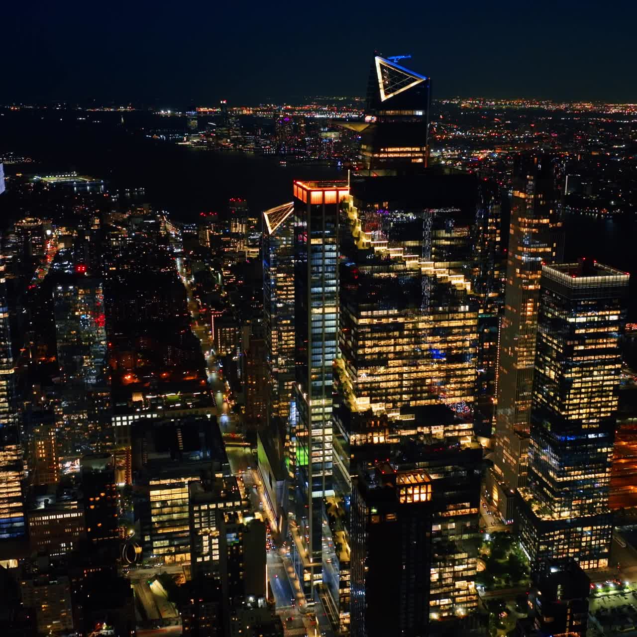 Sparkling cityscape of New York at night. Dark line of the river dividing the panorama. Top view