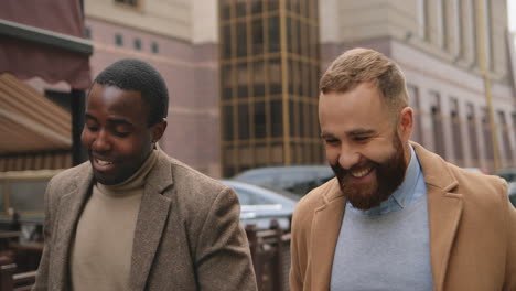 Caucasian-and-african-american-businessman-in-elegant-clothes-talking-and-walking-down-the-street