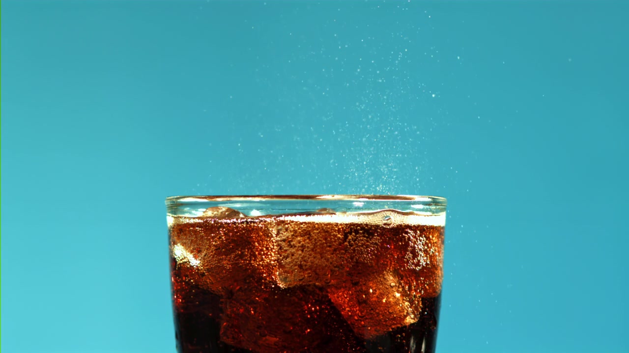 Bevanda cola frizzante con cubetti di ghiaccio su sfondo blu