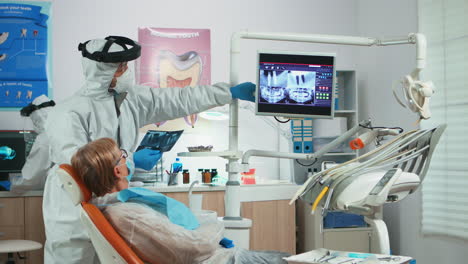 dentist with face shield reviewing panoramic mouth x-ray image