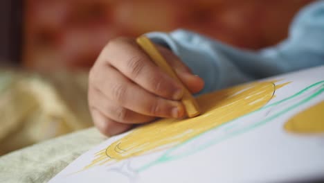 child's hand coloring with a yellow crayon