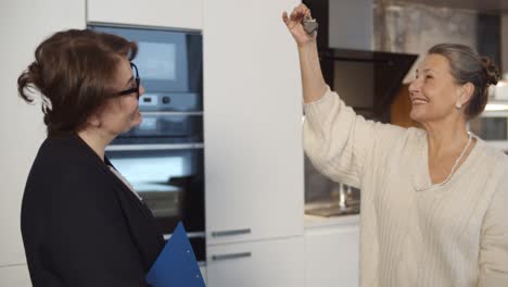 agente de bienes raíces dando llaves de un nuevo apartamento a una mujer feliz de edad