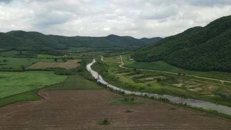 Aerial-footage-over-a-farmland-newly-tilled,-towards-a-gorgeous-landscape-with-a-canal,-farm-roads,-mountains-and-hills,-Muak-Klek,-Saraburi,-Thailand