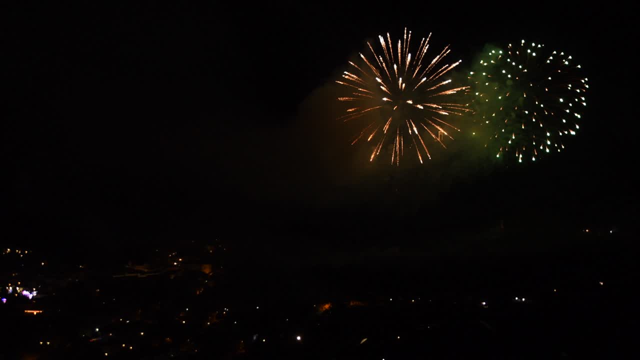 Celebration with many colorful fireworks, over a mountain town, at night
