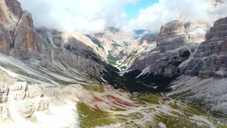 High-located-valley-surrounded-by-rocky-mountains,-white-clouds-on-sky