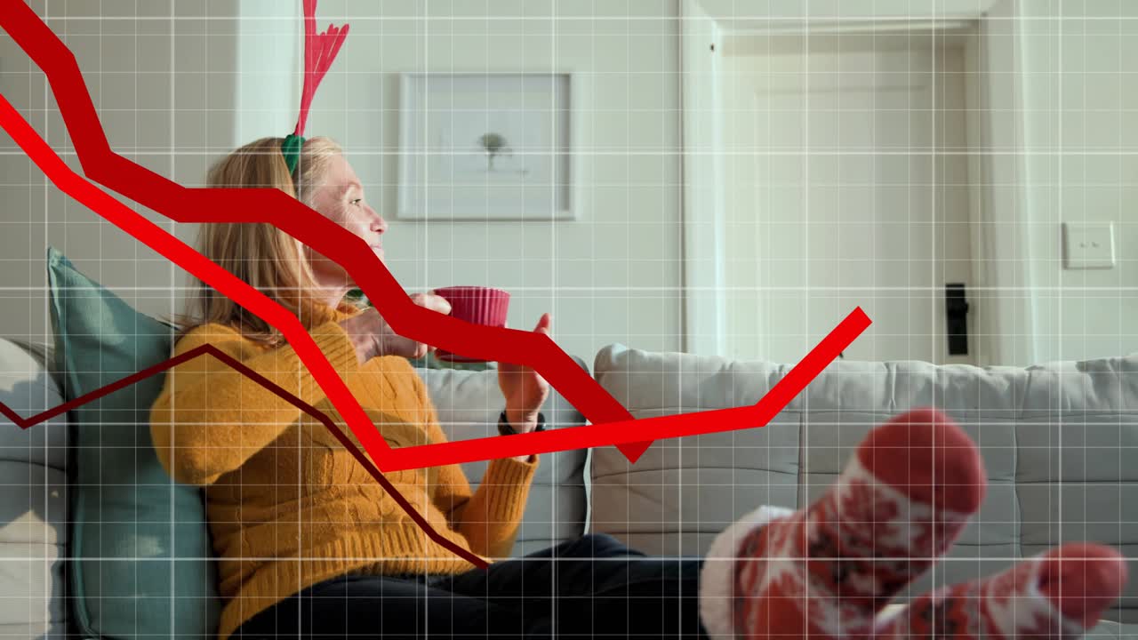 Woman on couch tapping tablet causing sweeping red lines across greeting holiday call sipping mug