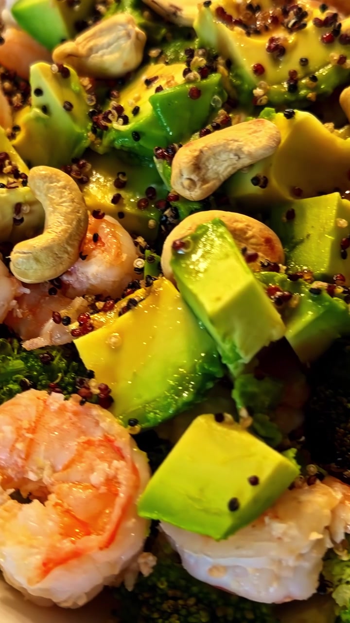 Dip di feta montata guarnito con pomodorini ciliegino arrostiti, aglio e olio d'oliva, e insalata sana di gamberi e avocado con quinoa e broccoli. - Scatto verticale.