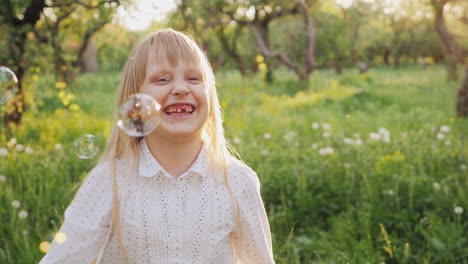 happy blonde girl playing with soap bubbles funny catches them slow motion video