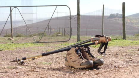 zapatos de senderismo y palos en el suelo sobre la valla y el campo, cámara lenta