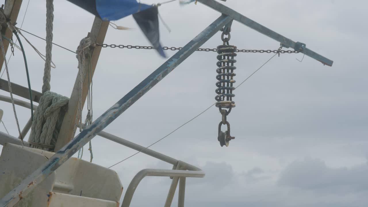 A commercial fishing vessel, pushed onto remote beach by recent heavy monsoon storms, now sits on side. Detail clip, ropes, steel, clip 9
