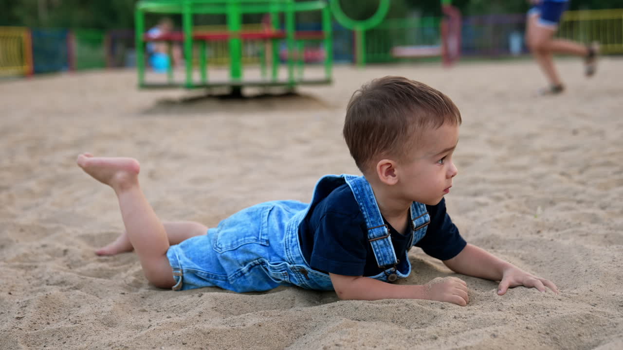 Bambino piccolo che gioca nella sabbia al parco giochi