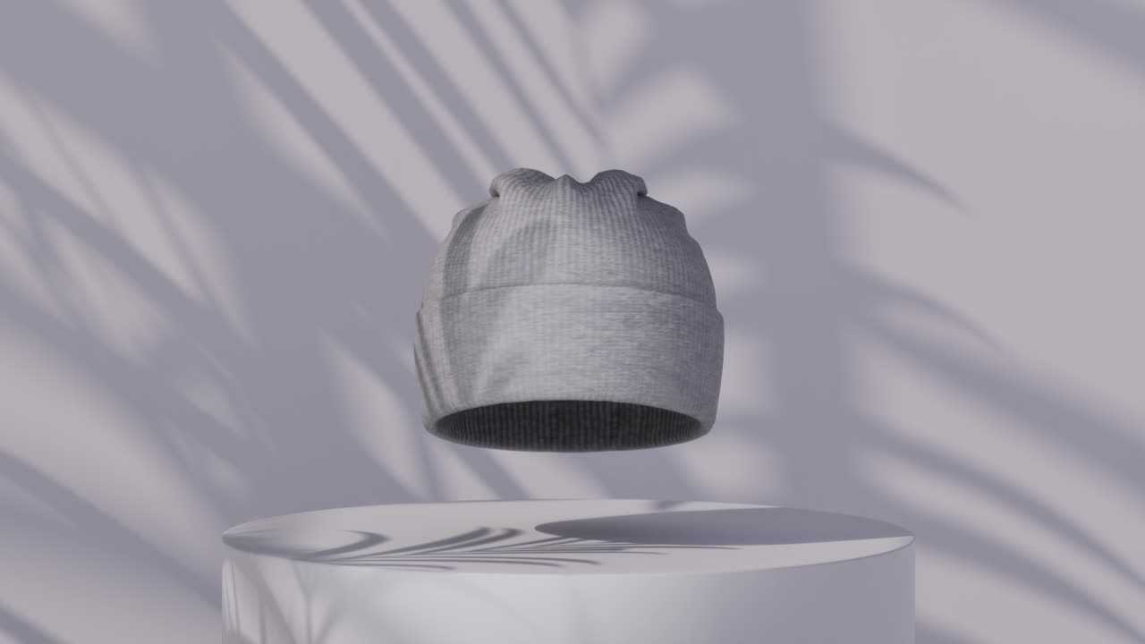 Gorro de punto gris flotando sobre un pedestal minimalista con sombras de palmeras