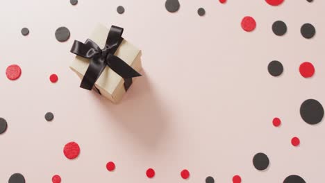 High-angle-view-of-white-gift-box-with-black-ribbon-on-white-with-red-and-black-dots-and-copy-space