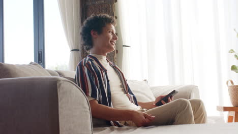 biracial man using smartphone for online shopping on sofa at home, slow motion
