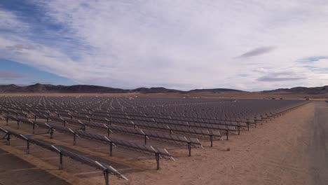 Aerial-Drone-Footage-of-Solar-Panel-Field-in-Joshua-Tree-National-Park-on-a-Sunny-Day-with-rainbow-in-the-background,-panoramic-revelation