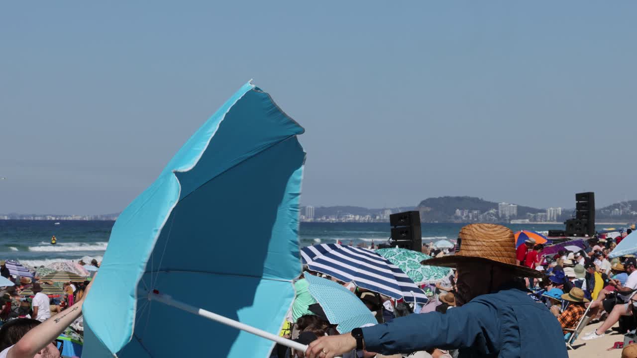 해변에서 바람에 쓰러지는 파란 우산