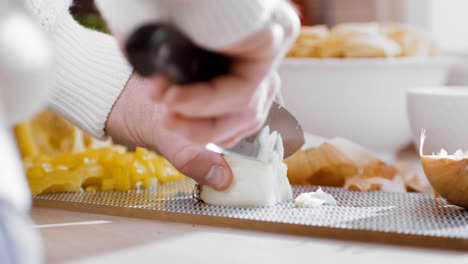 chef profesional masculino cocinando comida cena pirateando cebolla amarilla con un cuchillo afilado en la tabla de cortar haciendo deliciosa cena elegante cita romántica cocinando estofado pasta comida picante cocina soleada casa papá