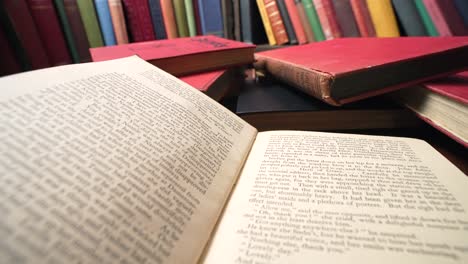 pile of red books sit on library table as center book is closed, reverse dolly