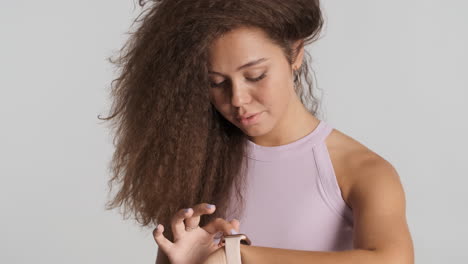 Caucasian-curly-haired-woman-checking-notifications-on-smartwatch.