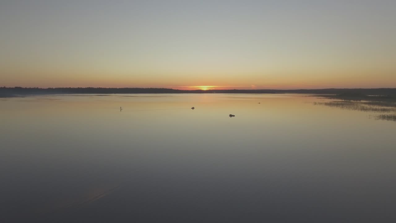 vuelo aéreo hacia los barcos en un lago tranquilo al atardecer