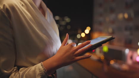 woman using tablet at night with city lights in background
