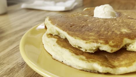 A close-up view of golden brown hotcakes with butter on top, evoking comfort food
