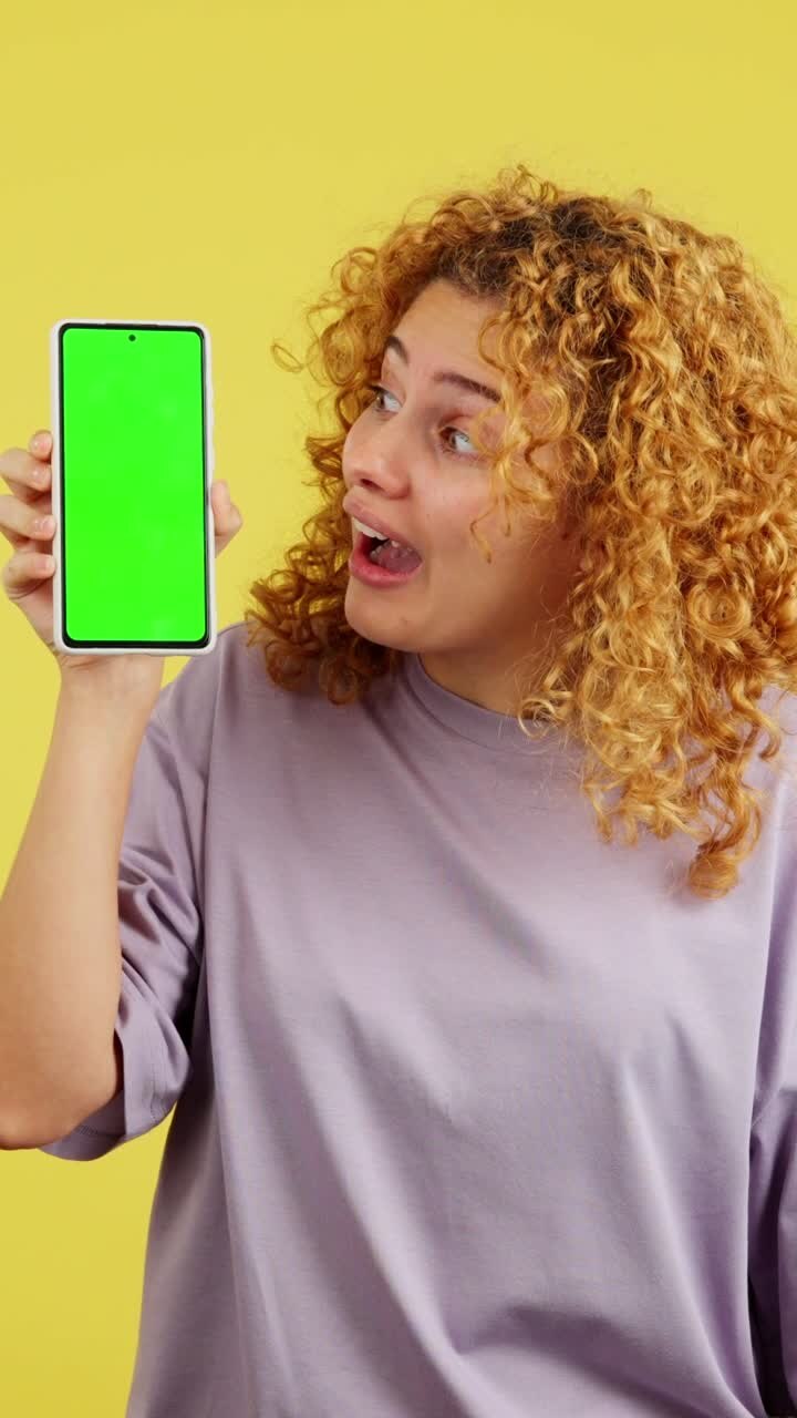 Woman reacting with surprise while holding a phone with a green screen