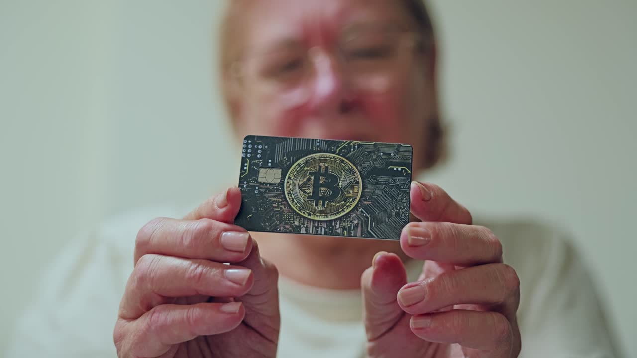Primo piano di mani anziane che tengono una carta bitcoin che simboleggia il flusso di denaro digitale