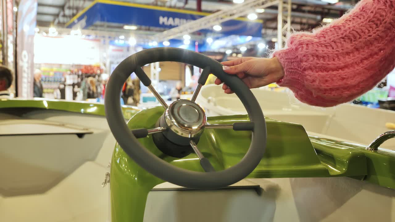 Close up of woman’s hand turning boat wheel at marine exhibition in Latvia