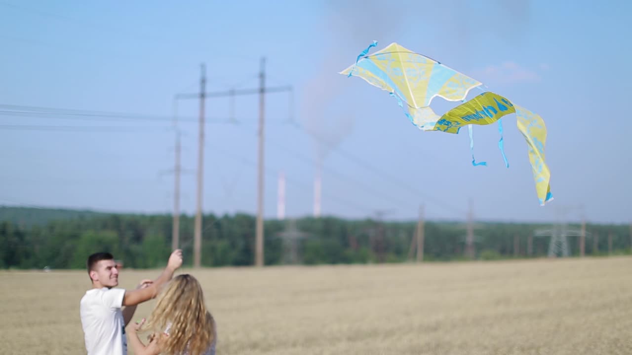 Love and Relationships. Playful young couple is running around the open field a flying a kite