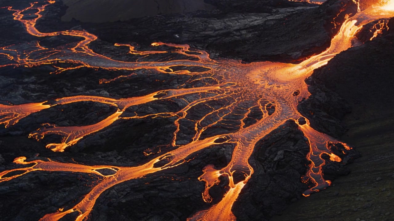 Sfiato eruttivo che alimenta lava che scorre su un campo di lava, formando canali intrecciati e una crosta che si raffredda.