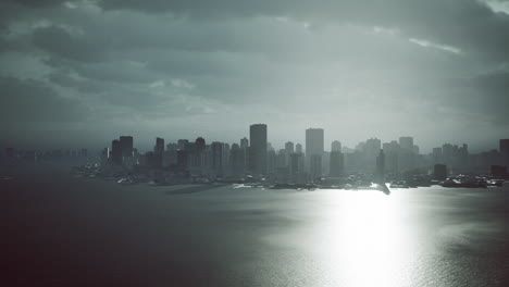 moody city skyline reflecting sunlight over water during cloudy afternoon