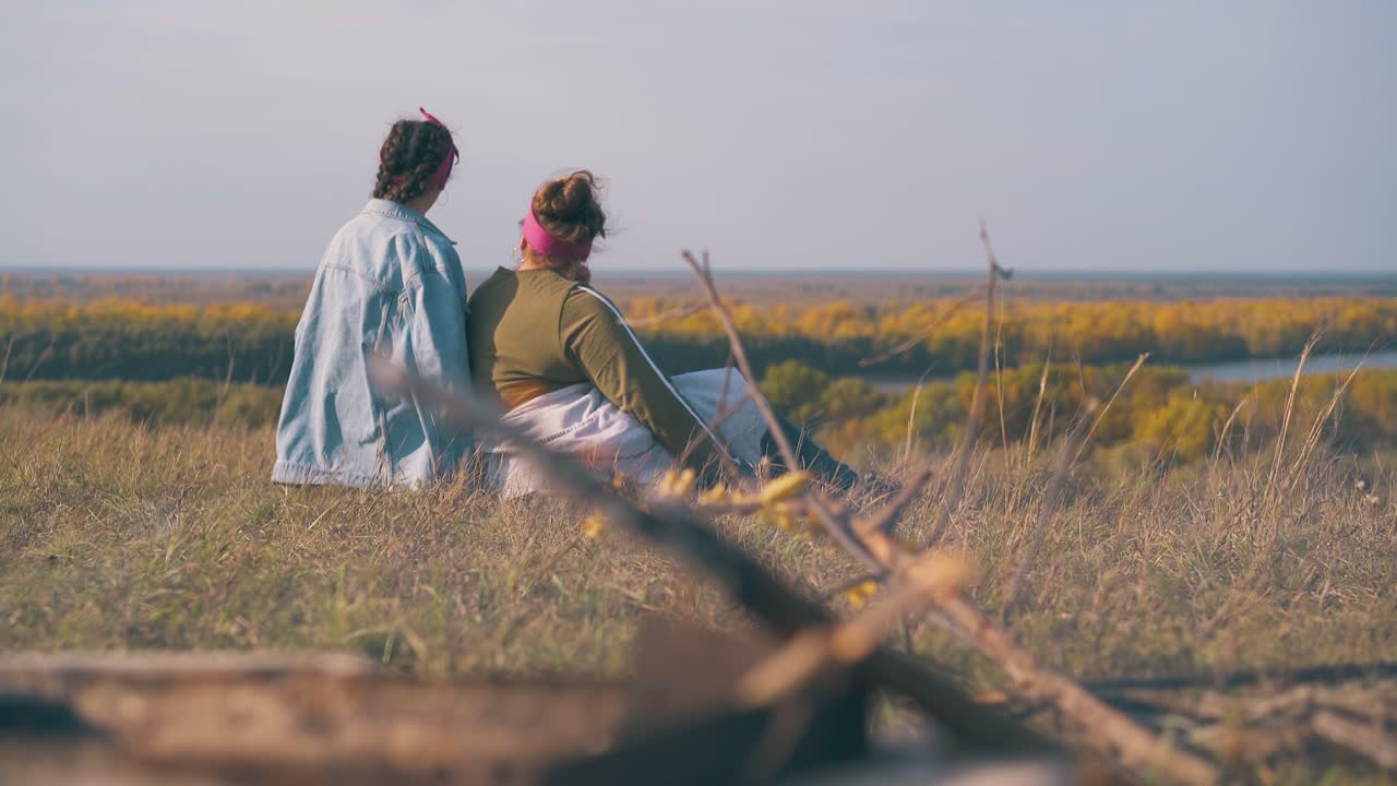 행복 한 여성 들 은 언덕 에 있는 강변 과 불꽃 에 있는 캠프 에서 휴식 한다