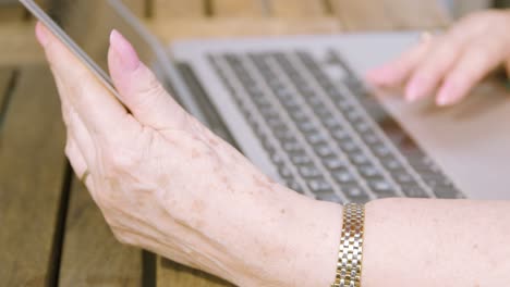 close up on elderly woman hands as she holds a laptop screen and scrolls on the trackpad