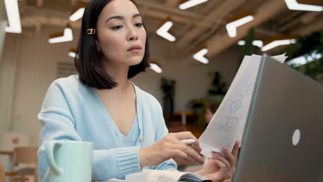 una mujer de negocios consultando documentos de trabajo en una cafetería 1