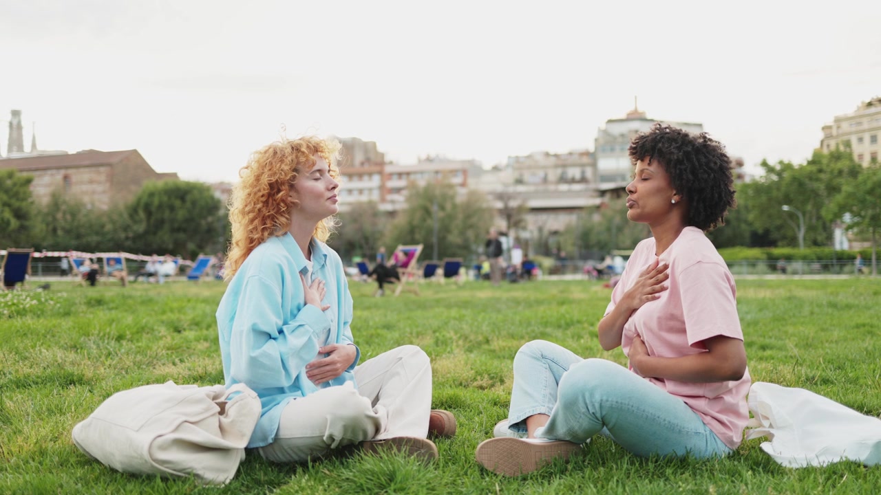 Due giovani donne che meditano all'aperto in un parco cittadino