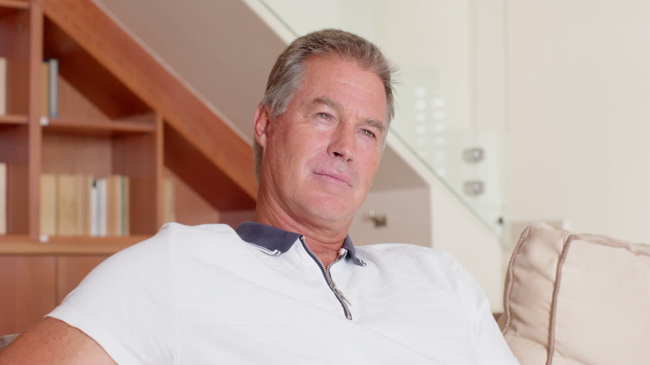 Older man relaxing at home, sitting on couch, looking thoughtful, copy space