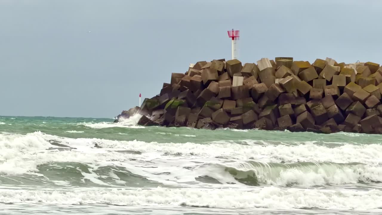 Kraftige bølger slår mod betonbølgebryder på Saint-Jouin-Bruneval strand, Normandiet i Frankrig