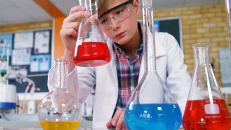 attentive schoolboy doing a chemical experiment in laboratory