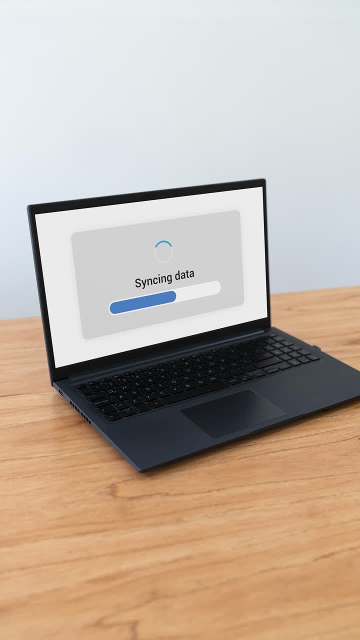 Vertical shot of laptop syncing data with cloud storage service.