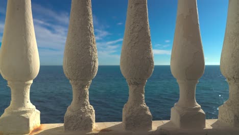 view of calm mediterranean sea through a concrete railing balustrade