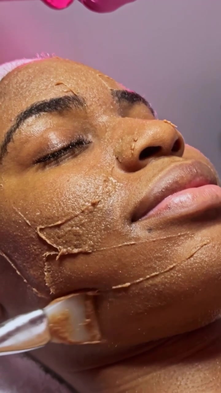 Professionista che applica una maschera per la cura della pelle sul viso di una donna.
