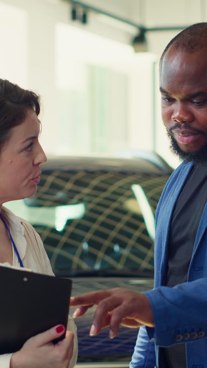 Venditrice di auto che discute con un cliente uomo in concessionaria