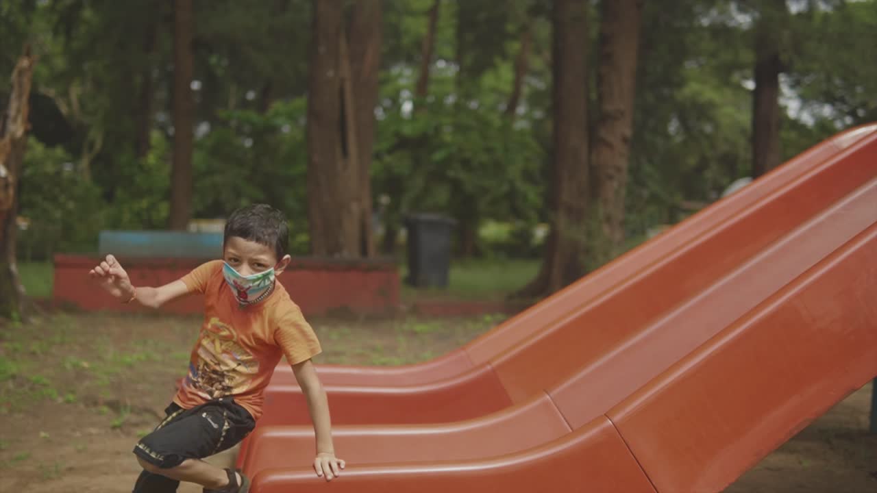 A small boy is happy when he goes down a slide in the children's playground