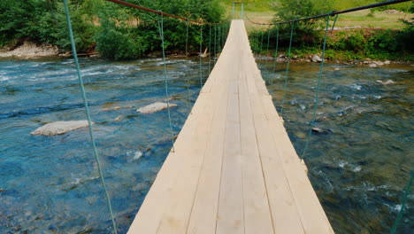 marcher sur un pont branlant à travers une rivière de montagne rugueuse