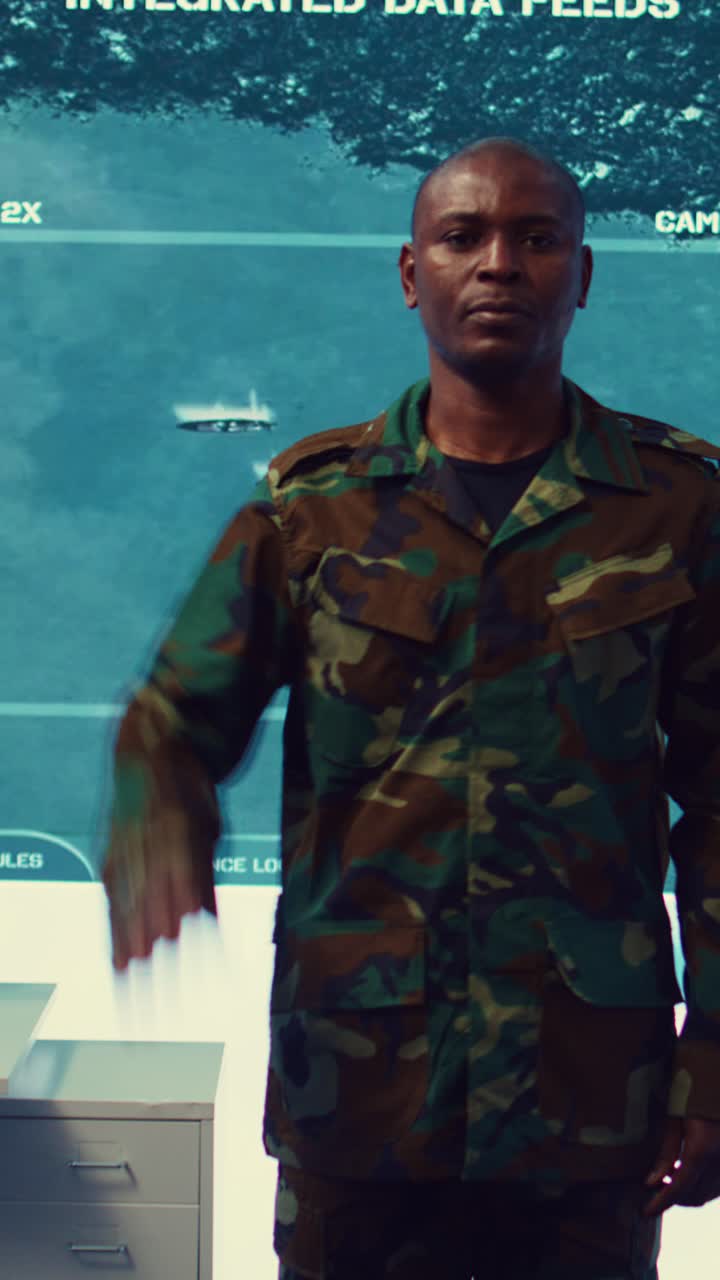 Uomo in uniforme militare mimetica che saluta in una sala di controllo
