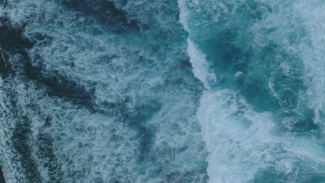 Top-Down-Slow-Motion-Drone-of-wave-action-at-low-tide-over-coral-and-rock-reef-Nyang-Nyang-Beach,-Bali,-Uluwatu-Indonesia