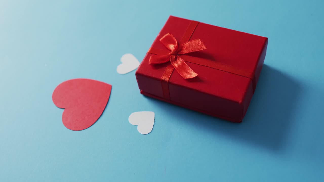 Paper hearts and present on blue background at valentine's day